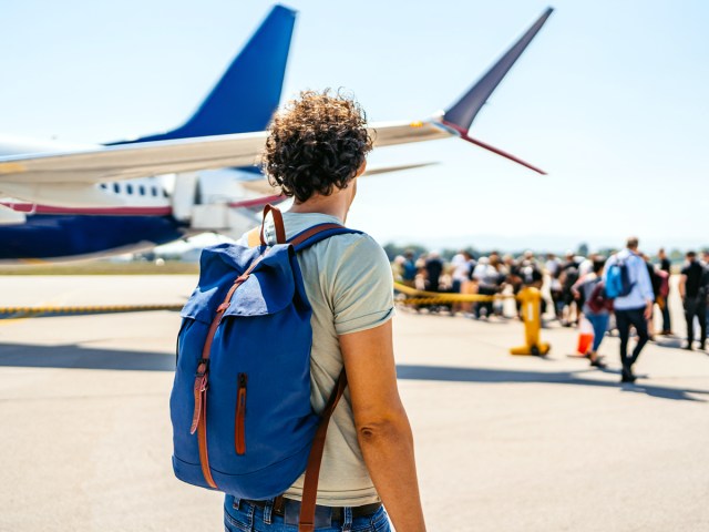 Man, seen from behind, walking to board plane on airport tarmac