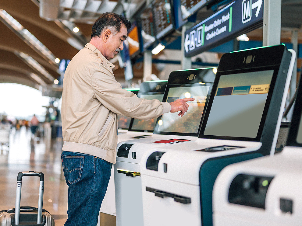 Traveler checking in for flight on self-service kiosk at airport