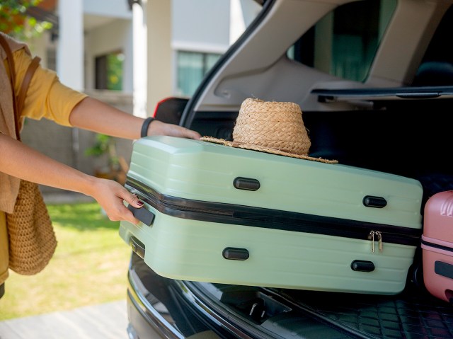 Close-up image of person placing suitcase in car trunk