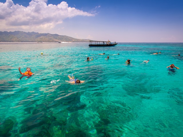 Snorkelers in translucent turquoise waters of the Gili Islands in Indonesia