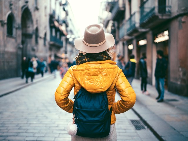 Tourist with backpack on street in Spain, seen from behind