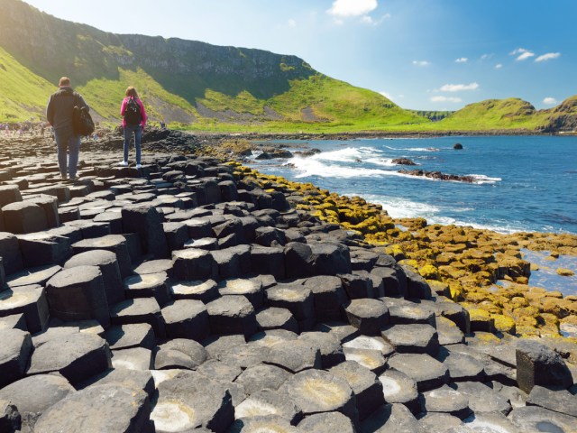 Two tourists walking on Giant's Causeway on Northern Ireland coast