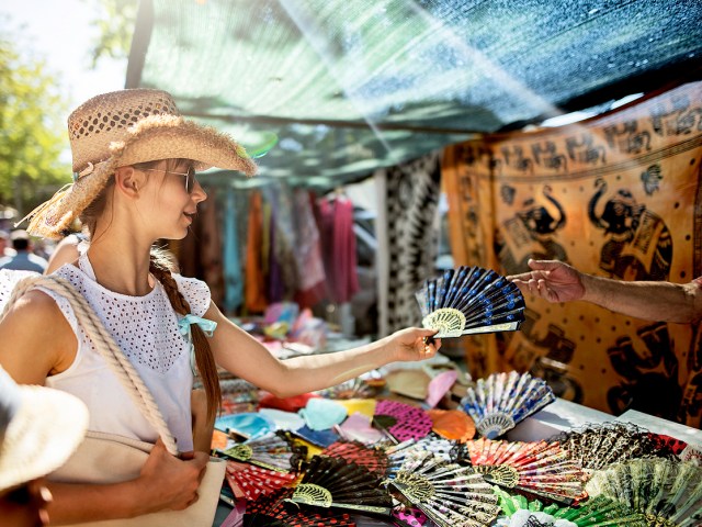 Woman at street market stall holding ornamental fan