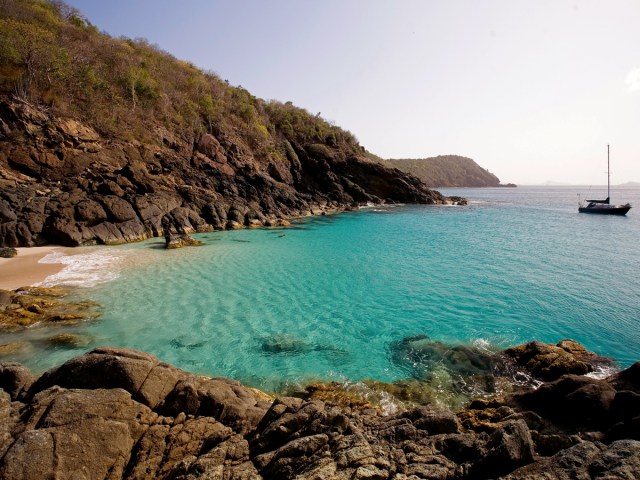 Cove with sandy beach, turquoise waters, and sailboat in the British Virgin Islands