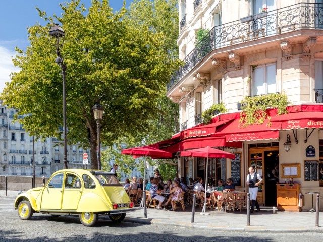 Vintage yellow car parked in front of Parisian sidewalk café