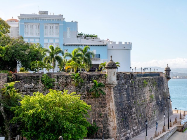 View of bright blue La Fortaleza palace and stone walls overlooking Caribbean Sea in San Juan, Puerto Rico