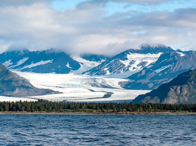 View of glacier and snow-covered mountains across bay in Alaska