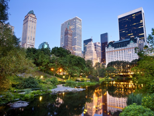 Manhattan skyscrapers reflecting onto lake in Central Park, New York City, at night