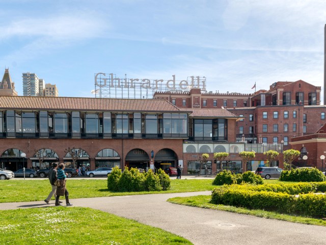 Couple walking in Ghirardelli Square with company sign in San Francisco, California