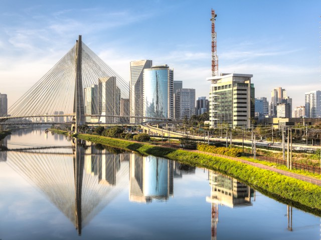 Suspension bridge over river with view of Sao Paulo, Brazil, skyline