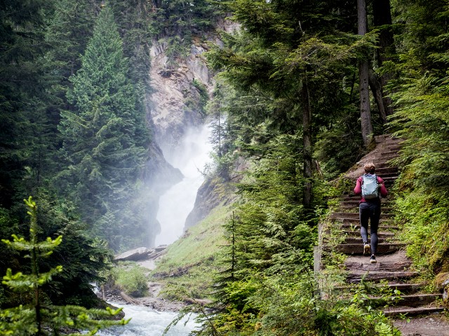 Hiker climbing steps beside waterfall