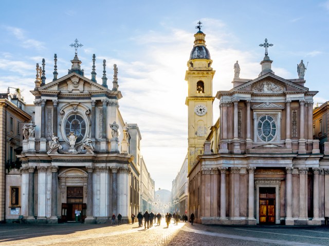 City square flanked by twin churches and clock tower in Turin, Italy