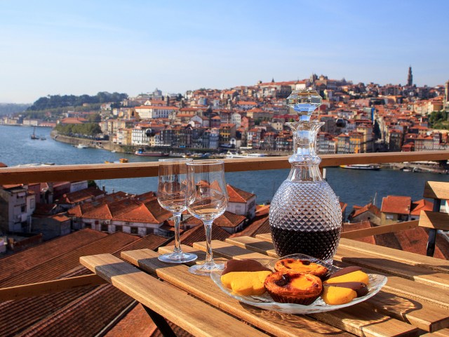 Close-up image of wine and meal on table overlooking river and cityscape of Porto, Portugal