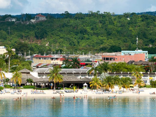 View of beach resort and dense foliage from across bay in Jamaica