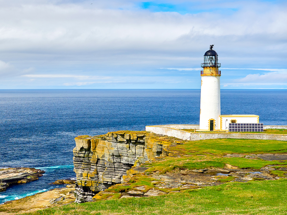 Lighthouse on rocky cliffs of the Orkney Islands in Scotland