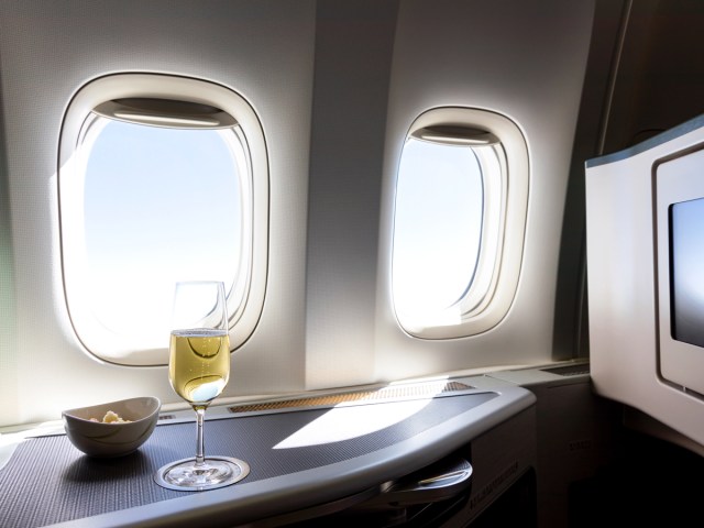 View out window, with glass of sparkling wine and ramekin in first class airplane pod