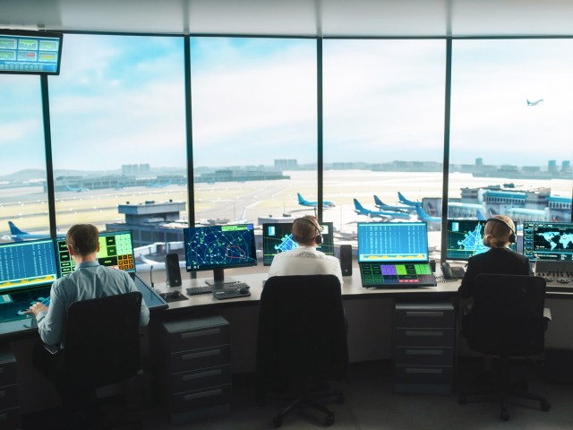 Flight dispatchers working in control center overlooking airport apron