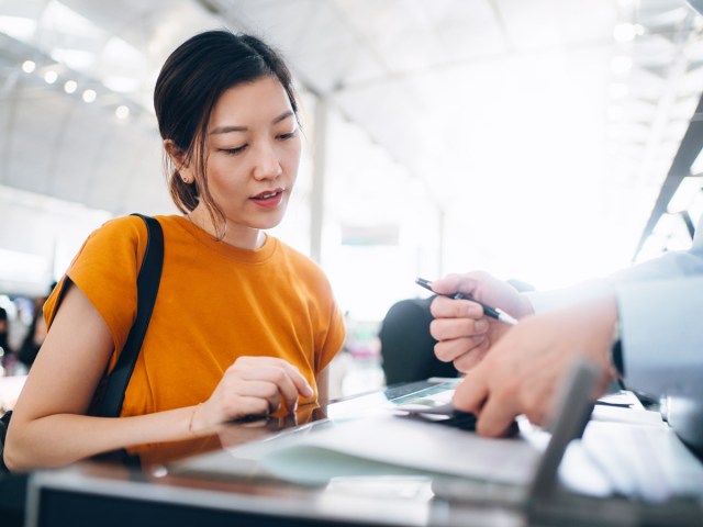 Passenger at airport ticket counter talking to agent