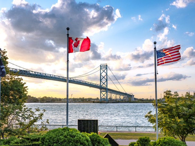 Flags of Canada and the United States along the Detroit River with the Ambassador Bridge in the background