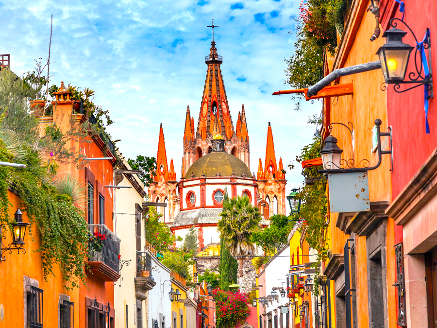 View of colorful church down street lined with brightly painted buildings in San Miguel de Allende, Mexico
