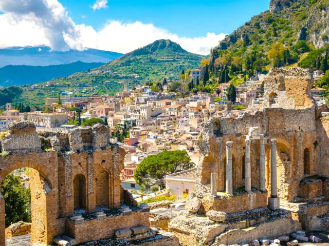 Ruins of ancient Greek theater and Mount Etna in the distance in Taormina on the island of Sicily, Italy