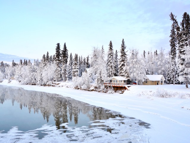 Home along icy lake and snow-covered landscape in Alaska