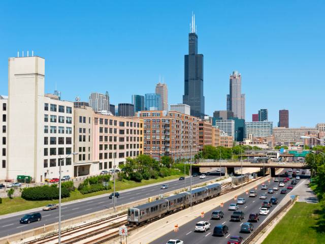 Cars and trains on Interstate 90 with downtown Chicago skyline in background