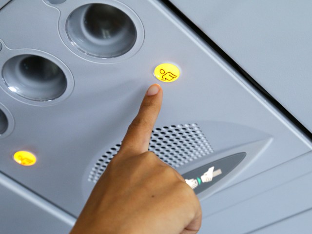 Close-up view of passenger pressing flight attendant call button on aircraft