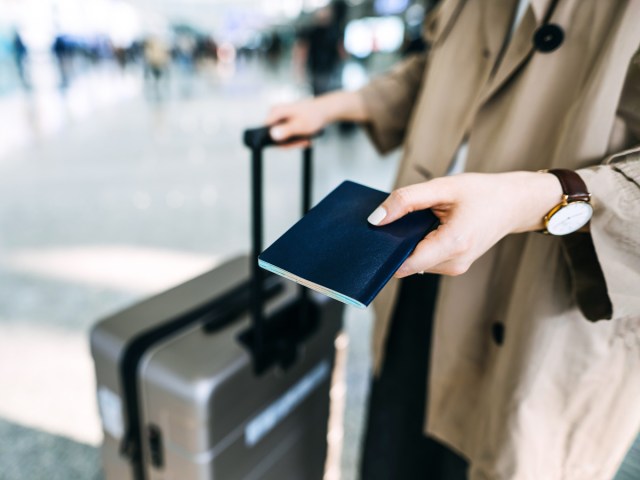 Close-up image of woman holding passport and luggage at airport