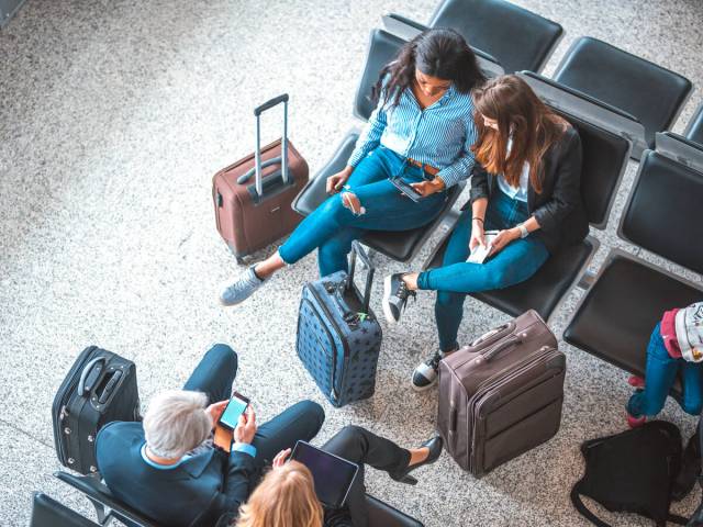 Travelers sitting at airport gate waiting area, seen from above