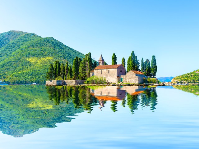 Small church on island with reflection on lake in Montenegro