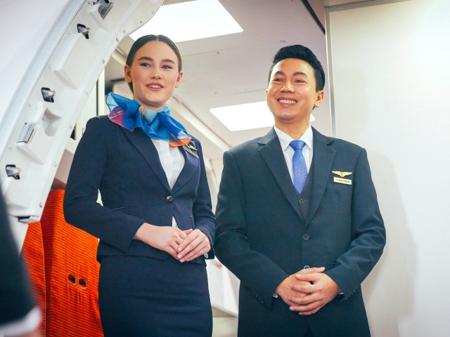 Flight attendants welcoming passengers on airplane