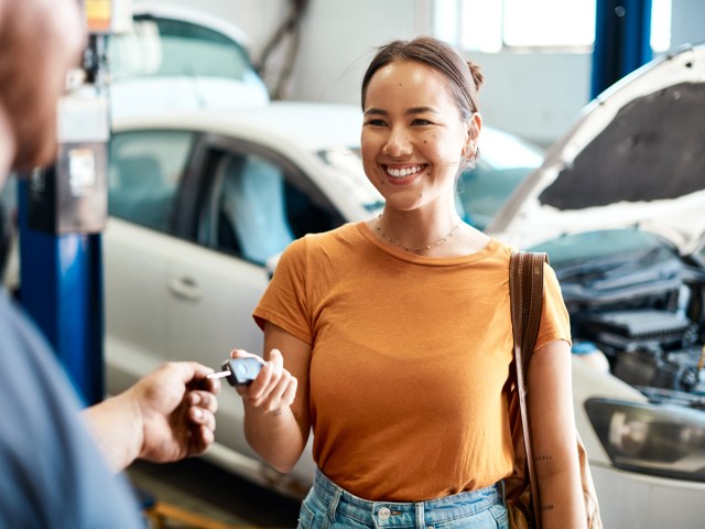 Driver handing keys to mechanic in repair shop