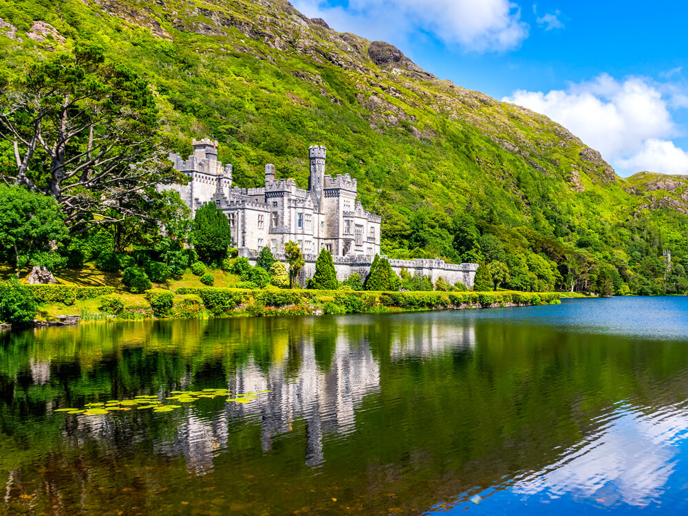 Castle beside lake and lush mountainside in Ireland