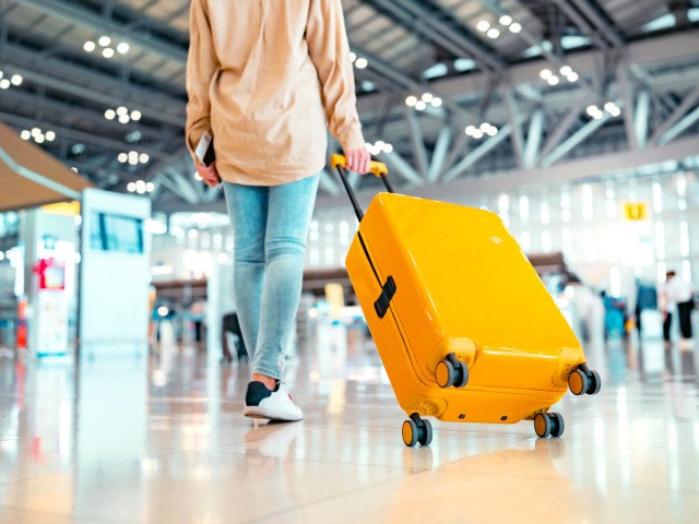 Traveler rolling yellow suitcase through airpot
