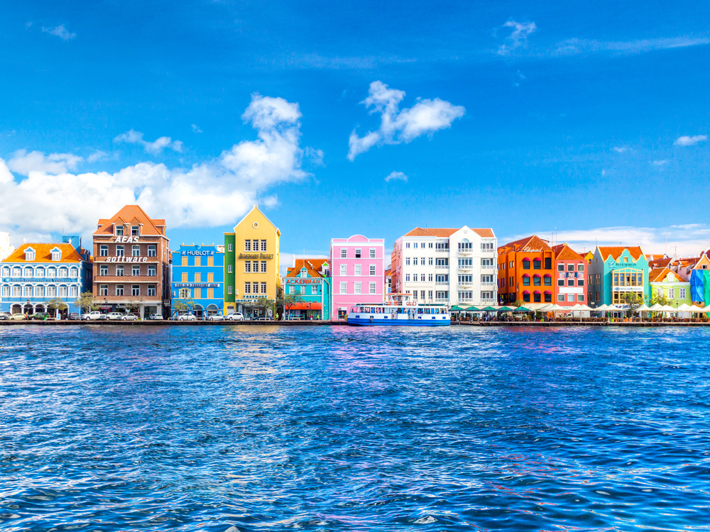 Rows of buildings in bold colors seen from across harbor in Willemstad, Curaçao
