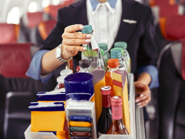 Zoomed-in view of flight attendant and beverage cart on airplane