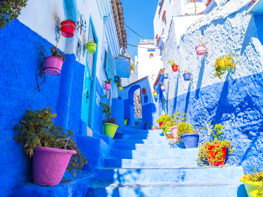 Staircase between stone buildings painted in bright shades of blue in Chefchaouen, Morocco