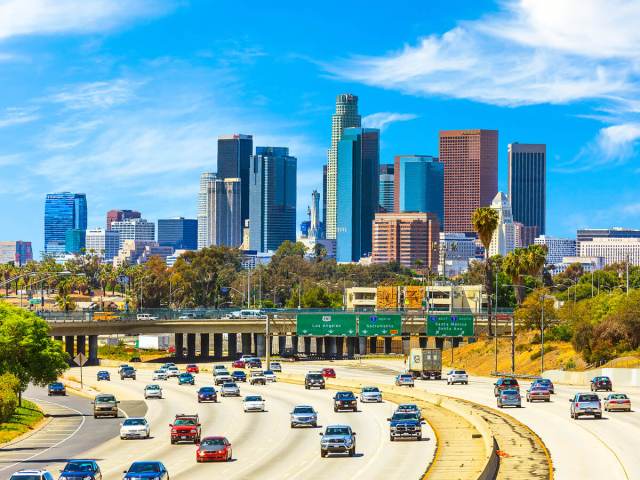 Cars driving on freeway with downtown Los Angeles skyline behind