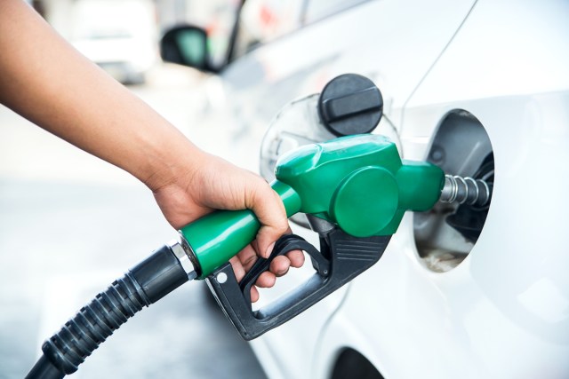 Close-up image of person holding gas pump nozzle at car fuel tank