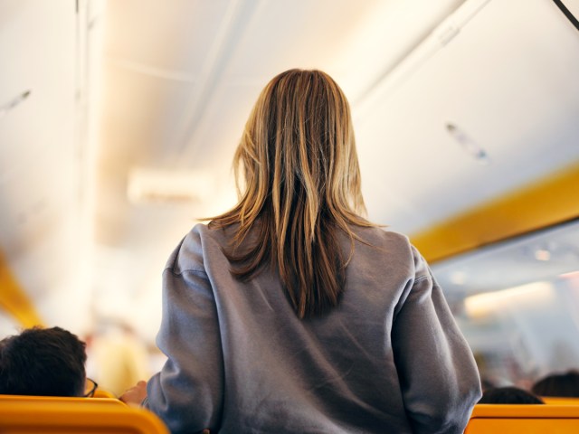 Passenger walking down aircraft aisle, seen from behind