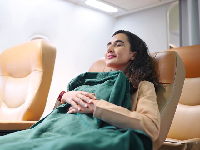 Traveler in blanket reclined in airplane seat