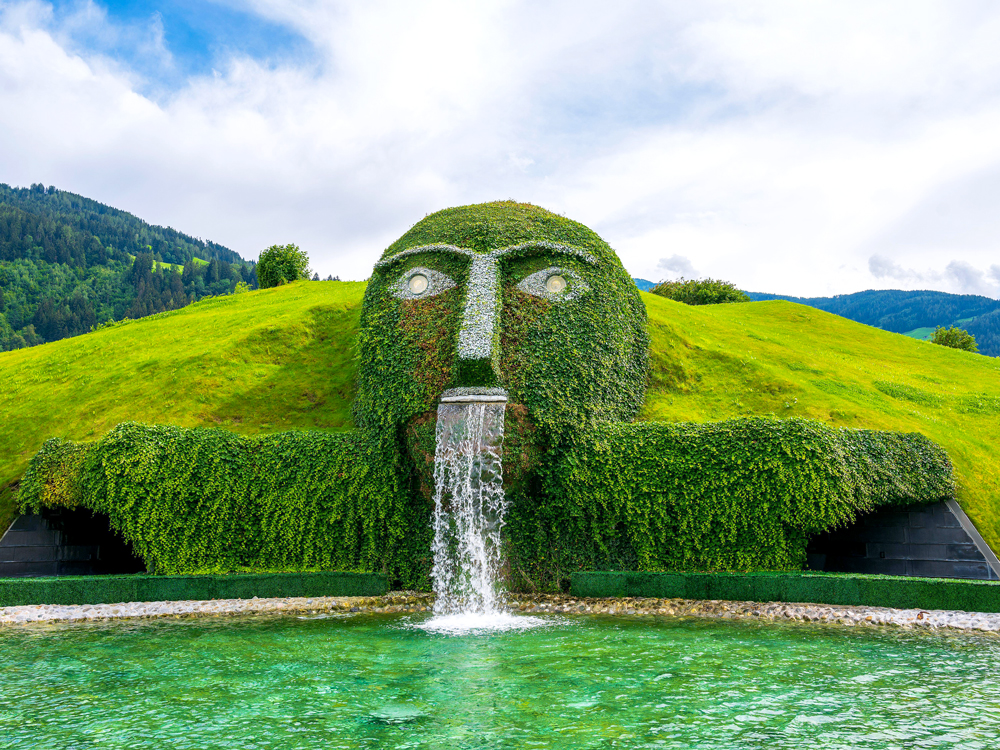 The Giant at Crystal Worlds in Wattens, Austria, depicting plant-covered giant with water spurting from month