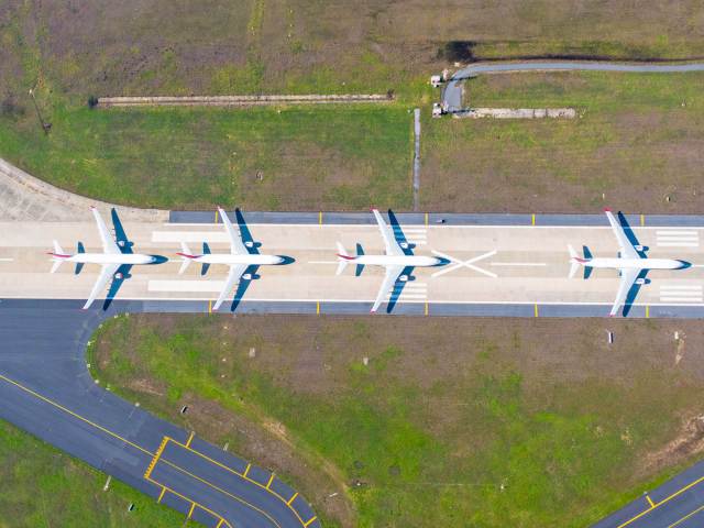 Overhead view of airplanes lined up on airport runway