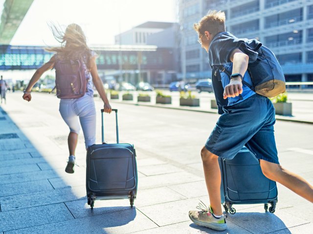 Travelers running with luggage outside of airport