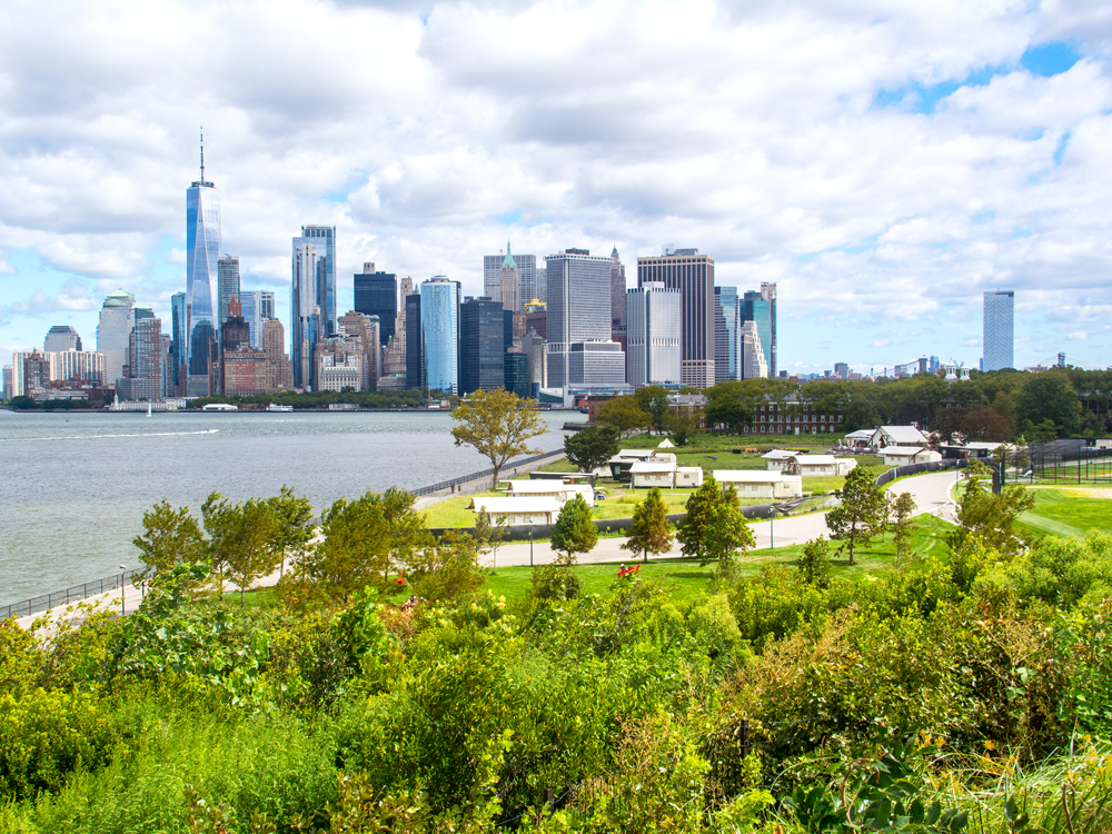 Parks and glamping tents on Governors Island in New York, with view of Manhattan skyline in background