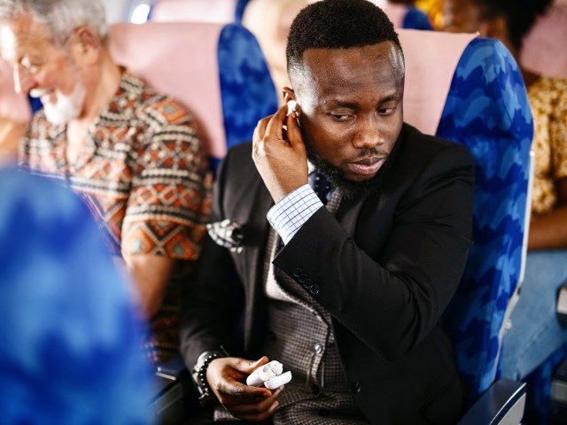 Traveler on airplane putting in earbuds