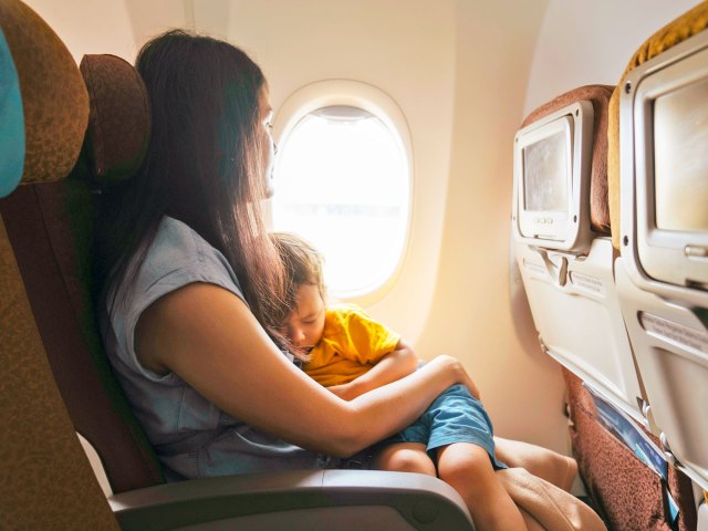 Toddler sleeping on mother's lap in airplane