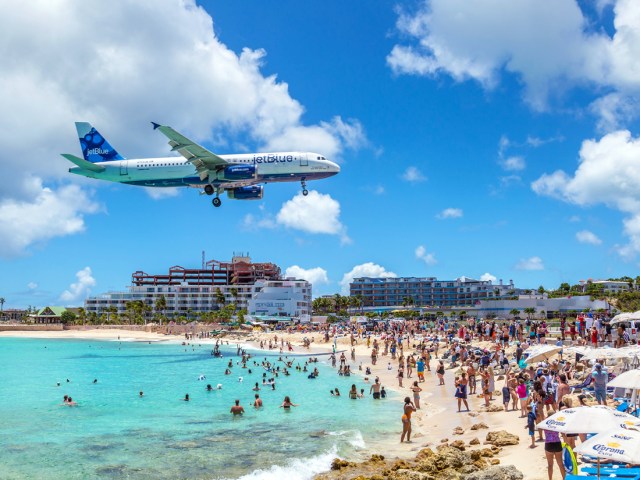 Beach goers in St. Maarten as plane flies low overhead