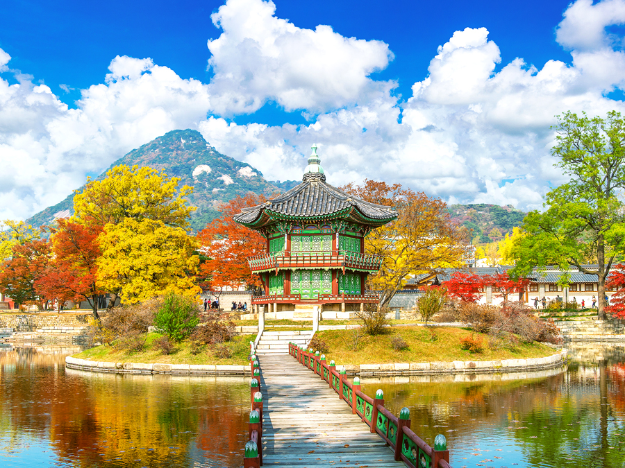 Gyeongbokgung Palace in Seoul, South Korea, surrounded by lake, mountains, and fall foliage